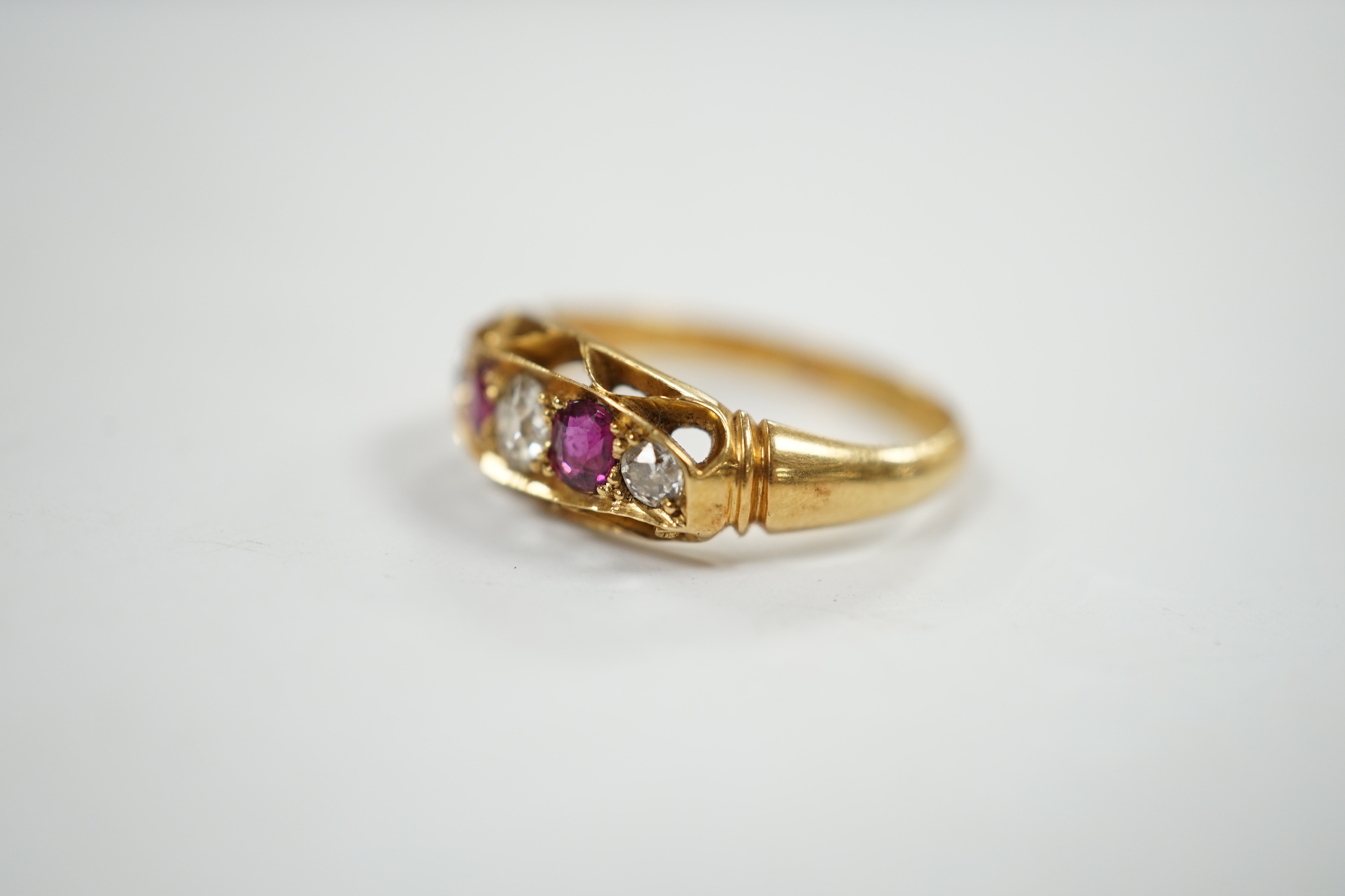 A George V 18ct gold, three stone diamond and two stone ruby set half hoop ring, size N, gross weight 3.8 grams.
